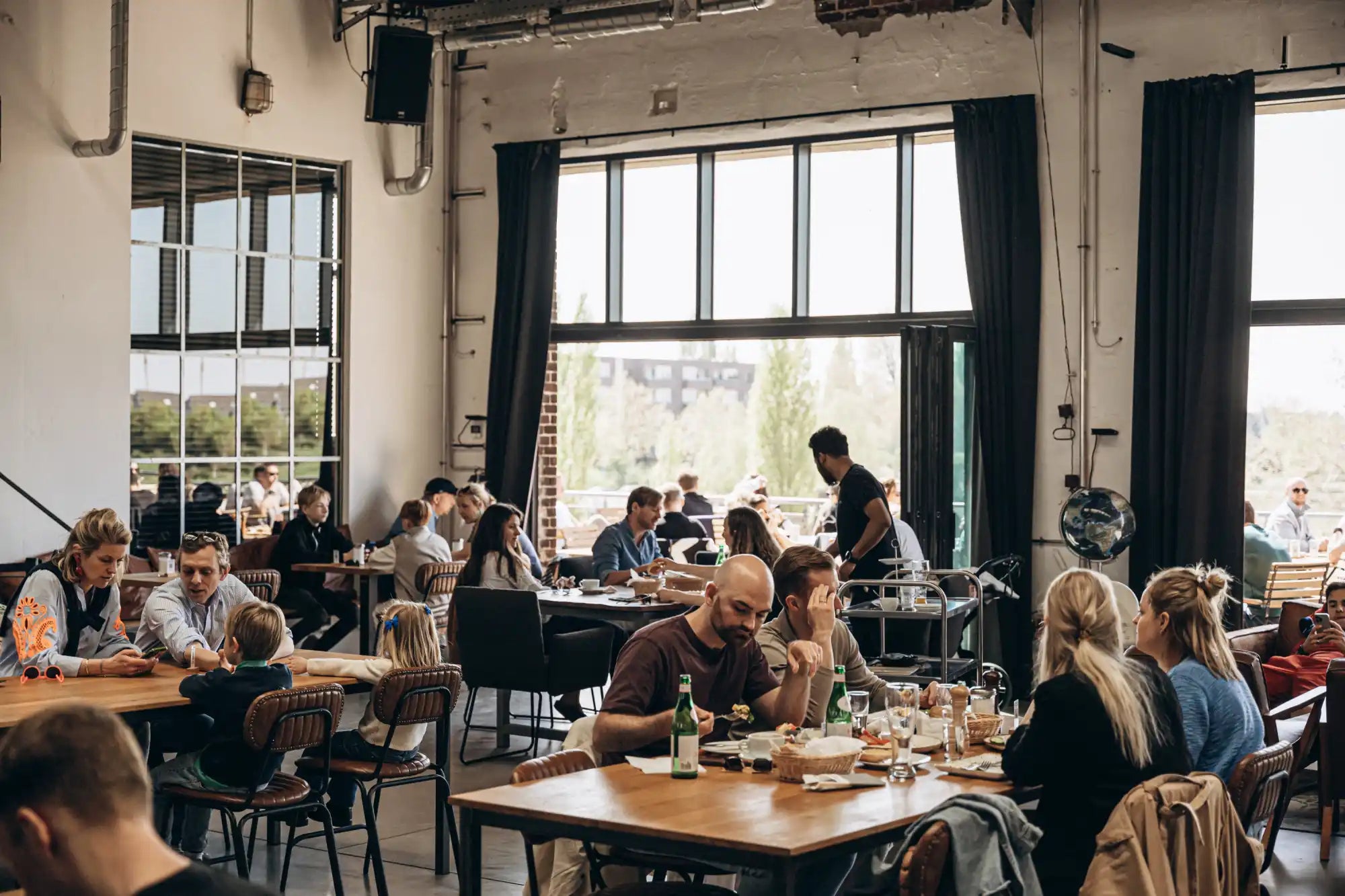 An airy restaurant with many patrons enjoying meals and drinks.
