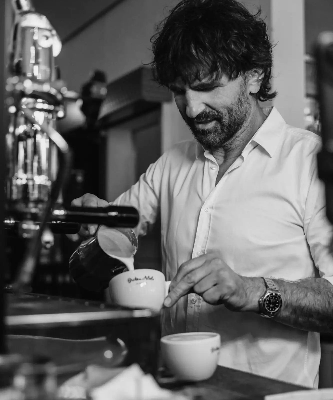 Barista pouring milk into coffee.