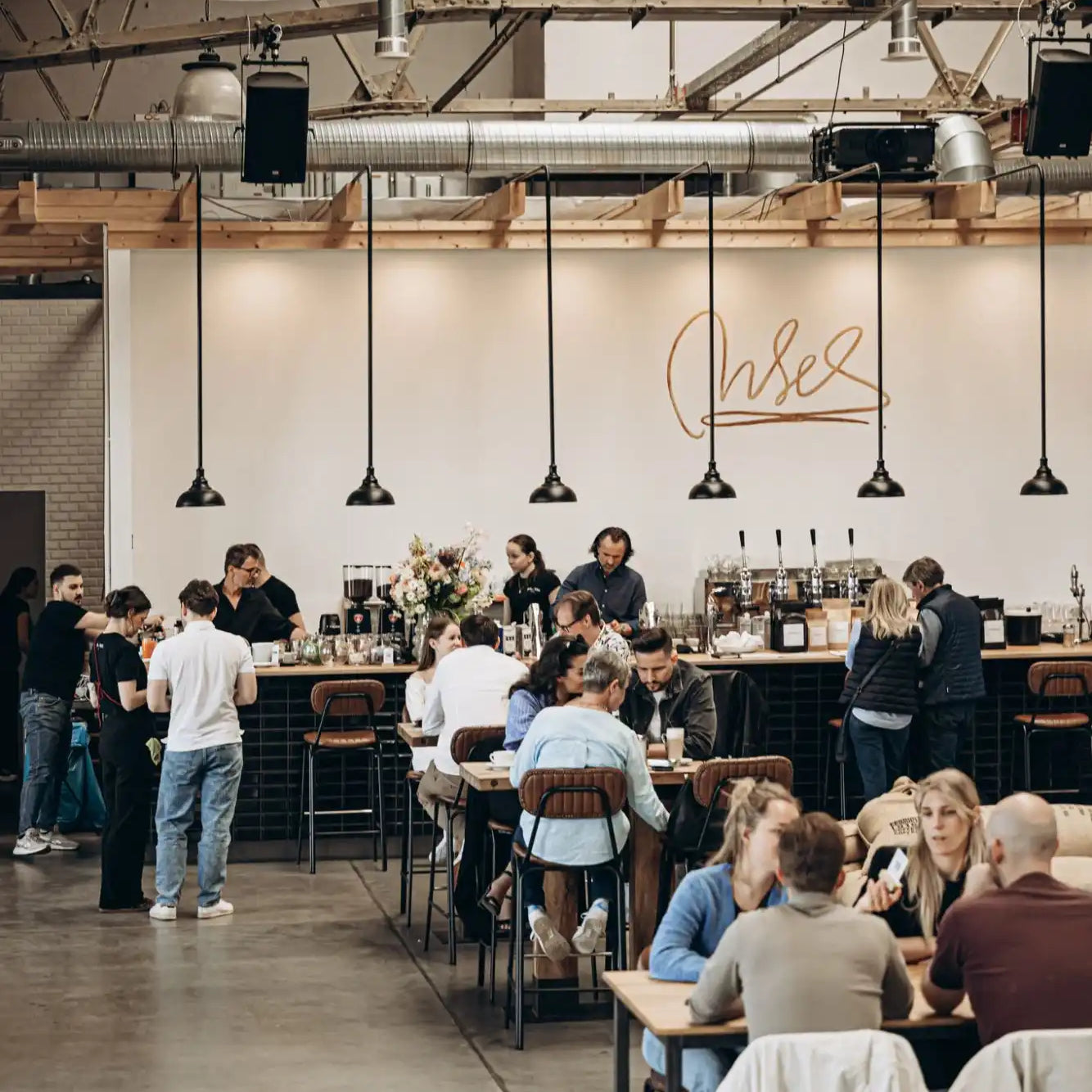 A busy cafe with customers at tables and a counter.