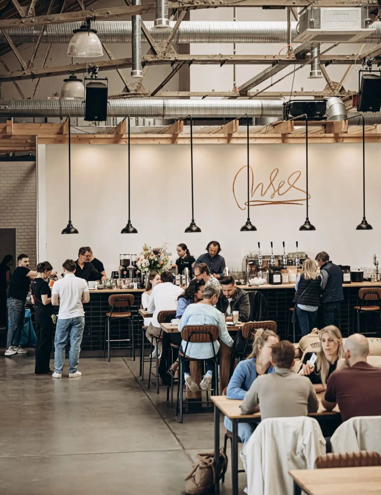 A busy cafe with customers at tables and a counter.
