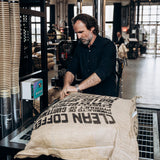 Dritan Alsela öffnet einen Sack Rohkaffee in der Rösterei