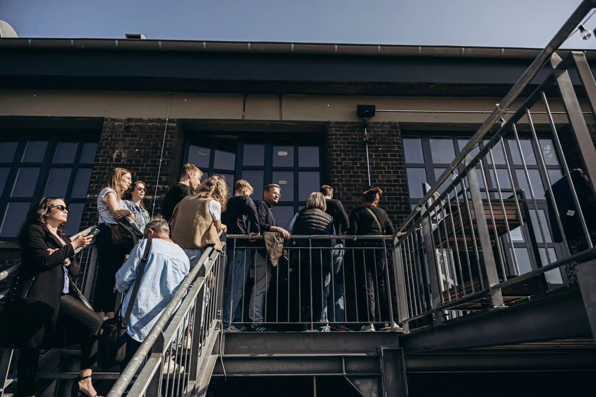 A group of people standing on an outdoor metal staircase and landing.