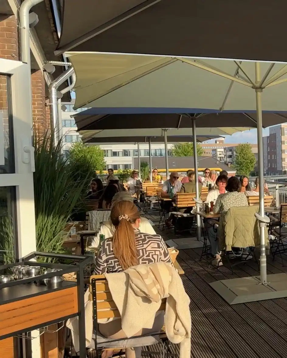 Outdoor rooftop restaurant patio with dining tables and umbrellas.