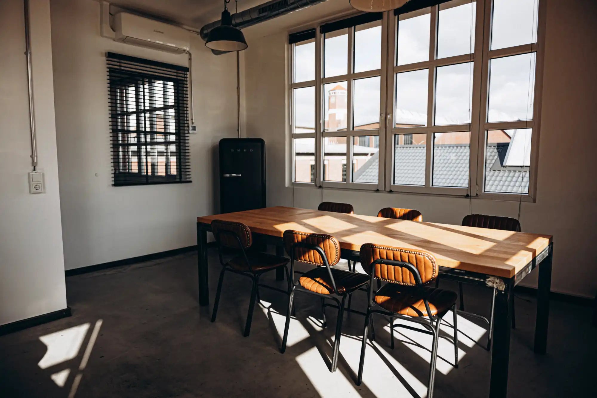 Wooden conference table with metal legs and orange cushioned chairs.
