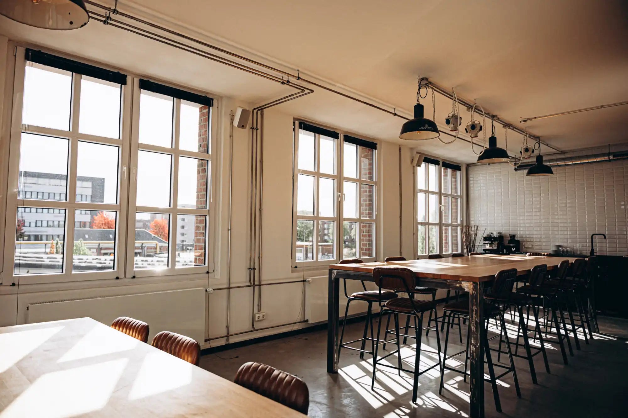 Wooden dining table with black metal chairs and pendant lights.