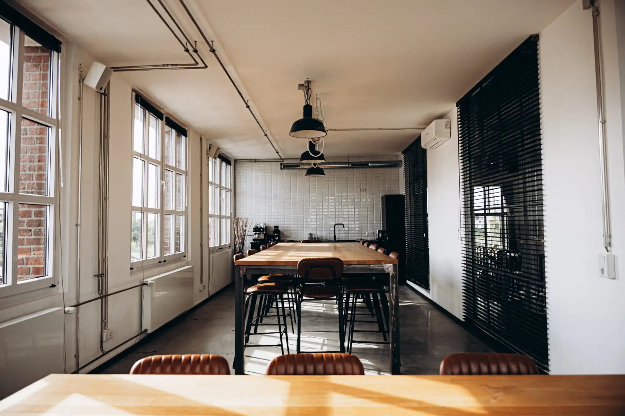 Wooden dining table with black metal legs and leather stools.